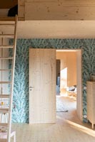 Open internal wooden door set in wallpapered feature wall