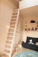 Timber clad children's room with ladder up to mezzanine bed 
