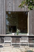 Outdoor dining area next to timber clad modern house 