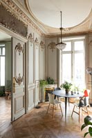 Small circular modern dining table in classic apartment filled with period details 