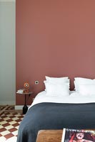 Modern bedroom with terracotta red feature wall and checkerboard flooring 