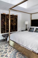 Gold four-poster bed in modern bedroom