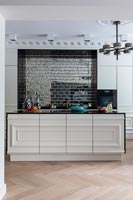 Large modern kitchen island with tiled feature wall and period details 
