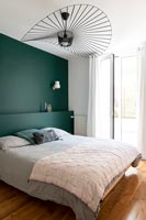 Teal painted wall and headboard in modern bedroom 