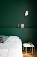 Dark green painted feature wall and headboard in modern bedroom 