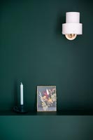 White sconce light on green painted wall with picture and candle 