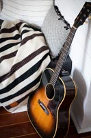 Close up of guitar next to blankets and cushions 