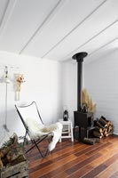 White butterfly chair next to wood burning stove in modern monochrome living room 