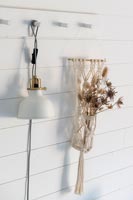 Detail of lamp and dried flower arrangement on white painted wooden wall 