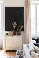 Plane black panel on living room wall above white shabby chic sideboard 