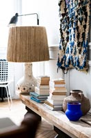 Large lamp and piles of books on rustic wooden bench 