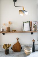 Shelf above kitchen worktop with recipe book and utensils 