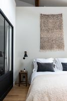 Fabric wall hanging above bed in modern bedroom 