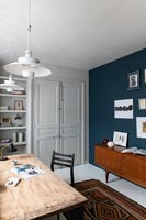 Vintage furniture and blue painted feature wall in modern study 