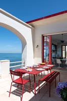 Red and white terrace with outdoor dining table and sea views 
