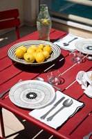 Lemons in black and white bowl on red outdoor dining table 