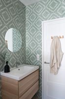 Muted green patterned wallpaper in modern bathroom 