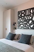 Black and white painting above bed in modern bedroom 