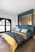 Colourful modern bedroom with headboard divider to en-suite bathroom area 
