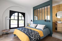 Colourful modern bedroom with view of screened off en-suite bathroom 