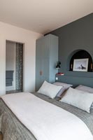 Modern bedroom with grey painted wall and view into en-suite bathroom 