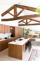 Exposed wooden beams over modern kitchen area in open plan living space 