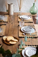Detail of wooden outdoor dining table laid for meal