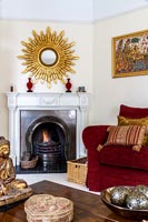 Large starburst mirror over mantelpiece in eclectic living room 