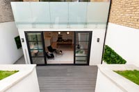 Exterior of house with modern basement extension and sunken decked terrace 