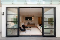 View into modern monochrome open plan living space through sliding patio doors 