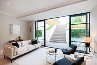 Modern monochrome living room with view through open patio doors to sunken terrace 