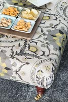 Patterned foot stool used as coffee table with tray of snacks