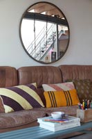 Large round mirror above old leather sofa 