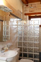 Exposed stone wall in modern bathroom with glass block wall of shower cubicle 