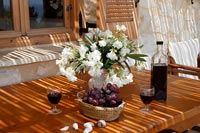 Flower arrangement, grapes and wine on outdoor dining table 