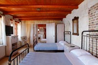 Two double beds in country bedroom with exposed wooden beams and brickwork walls 