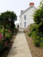 Paved pathway leading through garden to house 