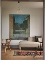 Large painting on wall of country living room framed by doorway 