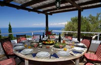 Large circular outdoor dining room under pergola with sea views from terrace 