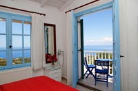 Mediterranean country bedroom with open French doors to balcony with sea views 