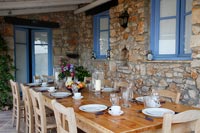 Outdoor dining room on terrace next to stone cottage 