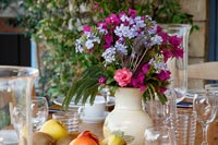 Detail of flower arrangement on outdoor dining table laid for lunch 