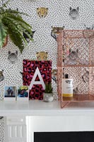 Wild animal wallpaper with pictures and ornaments on mantelpiece 