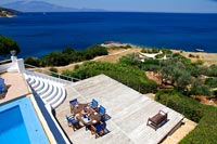 Overview of swimming pool and decked seating area with sea views 
