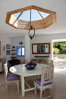 Country dining room with circular wooden skylight windows above table 