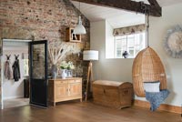 Exposed stone wall and beams in country living room with swing chair 
