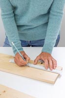 Woman using a ruler to measure and mark were to drill holes for pots