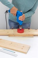 Woman using a holesaw bit to make 10cm holes in board