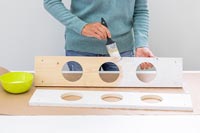 Woman using a paint brush to paint the shelves