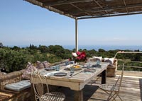 Outdoor dining table on wooden terrace with coastal views 